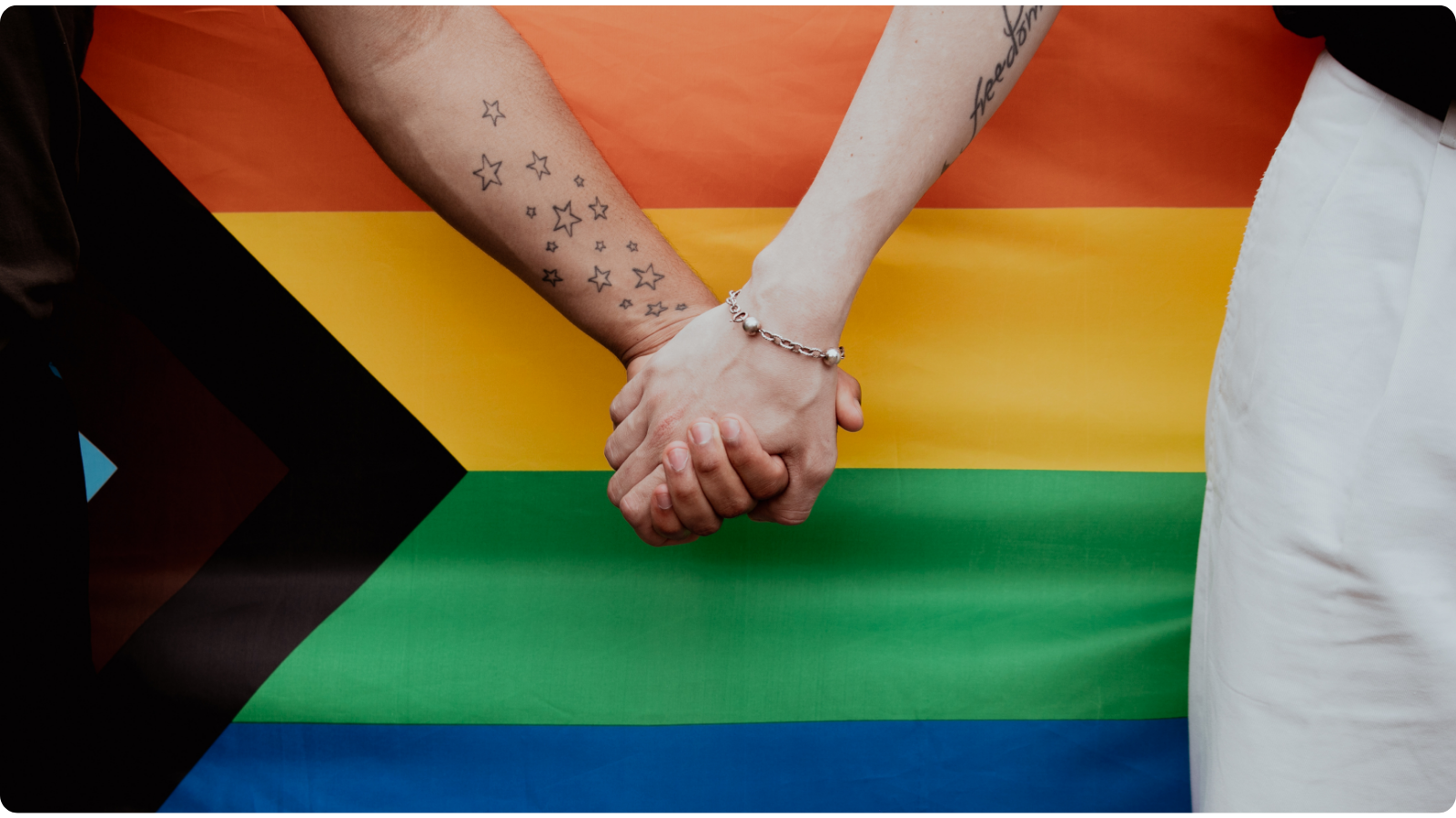 2SLGBTQIA+ flag and two people holding hands